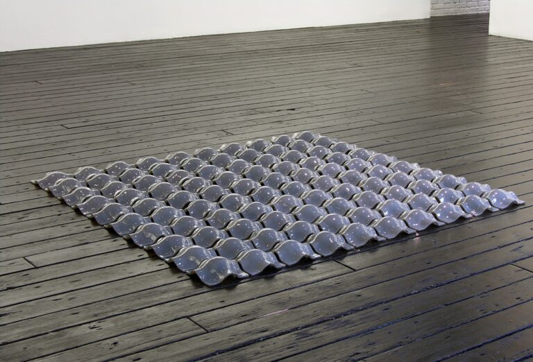 An arrangement of blue-violet glass forms on a wood floor.