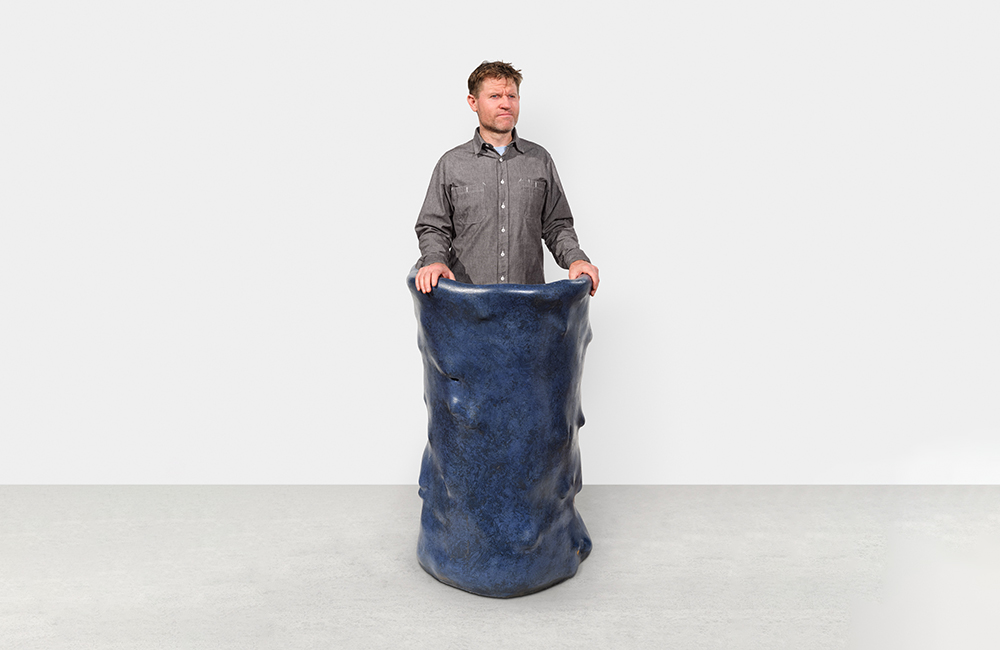 A person standing behind a large blue podium with a lumpy surface